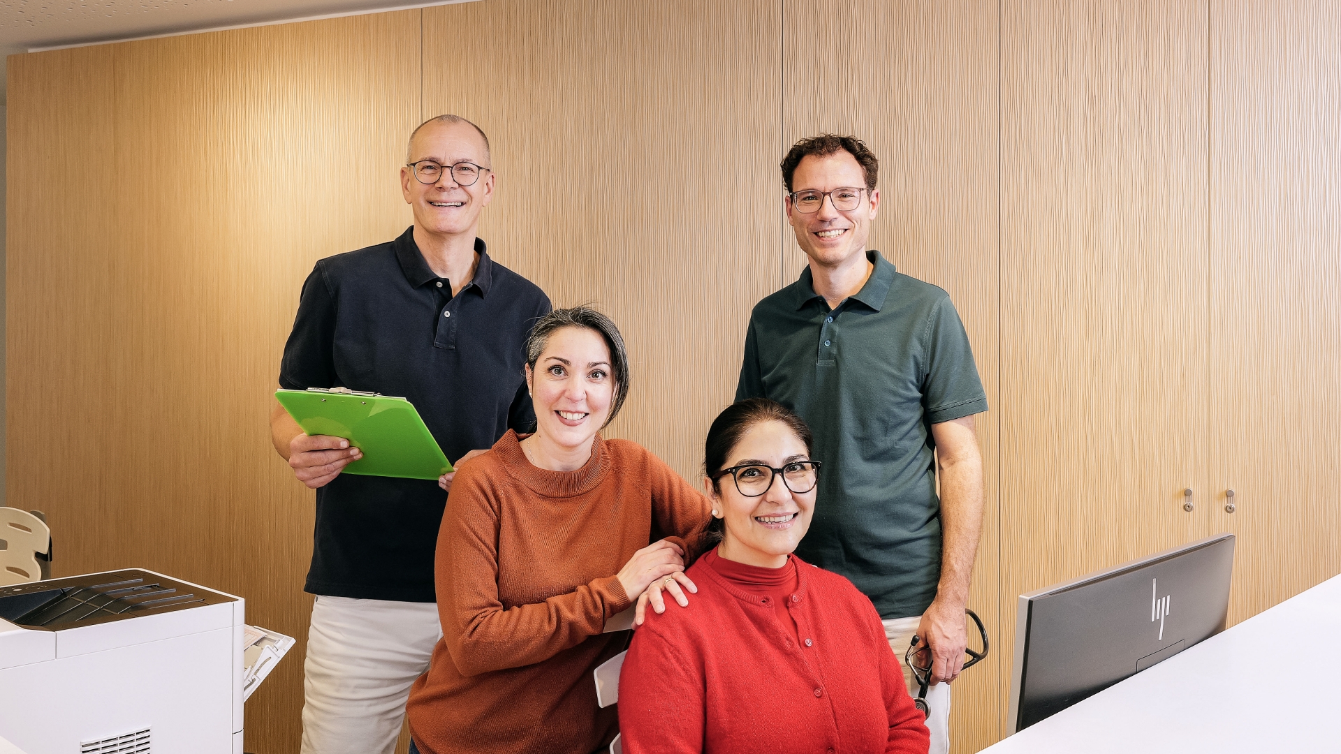 Team mit zwei Ärzten, hinten stehen und zwei weiblichen Angestellten davor